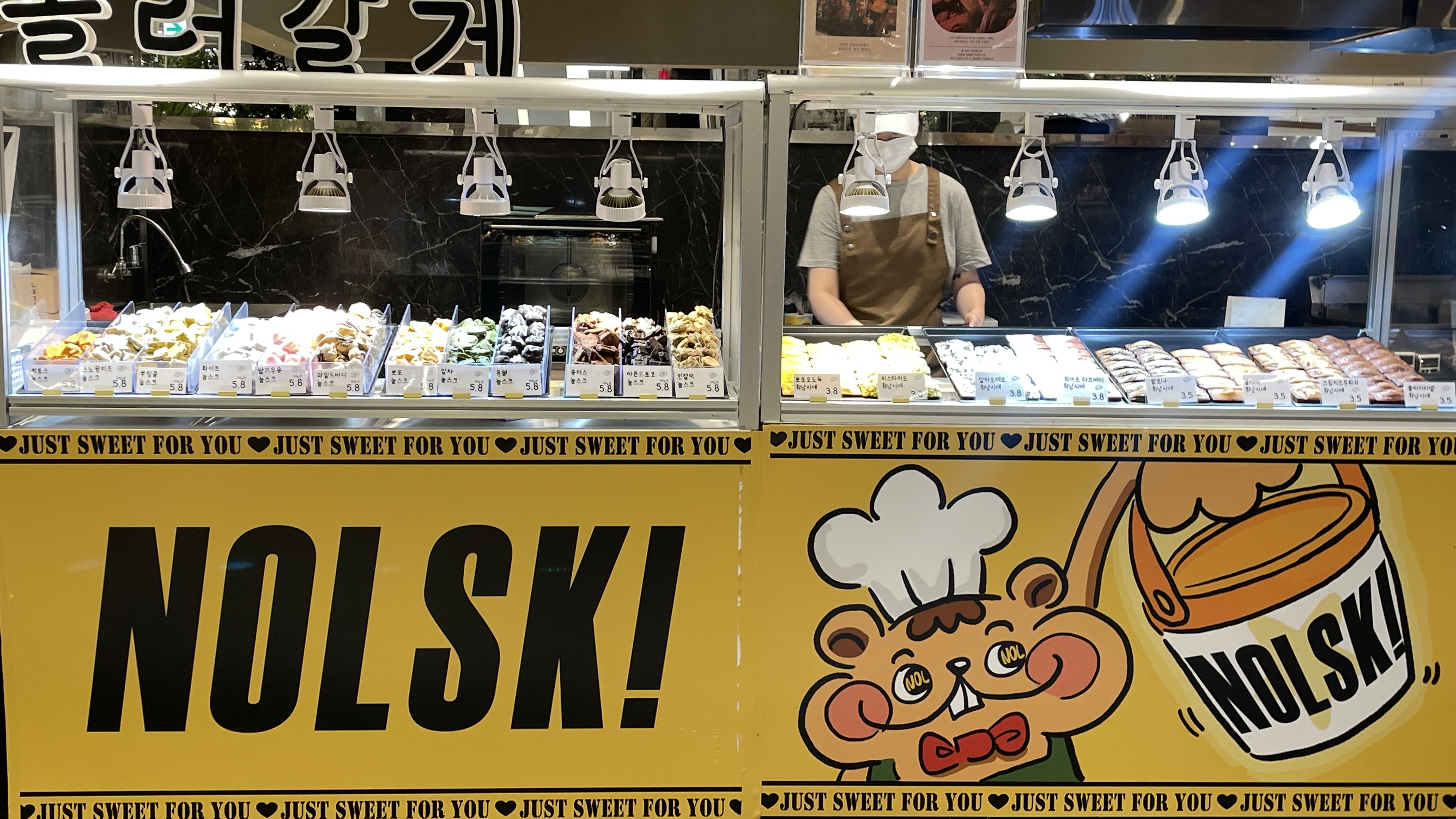 Vibrant NOLSK bakery display case with colorful desserts and squirrel mascot decor